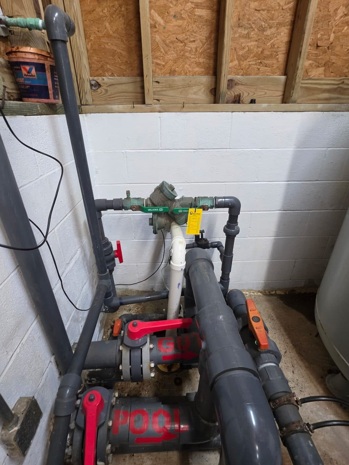Pool backflow preventer connected to PVC piping labeled for pool and city water