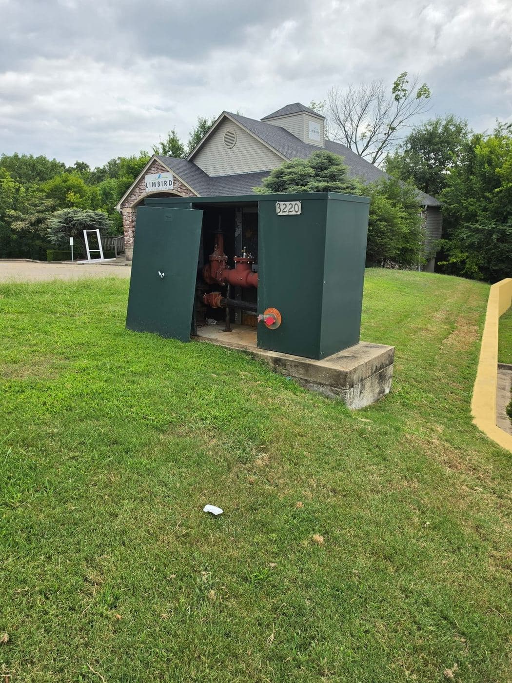 Green backflow enclosure open to show a red valve assembly at a commercial building